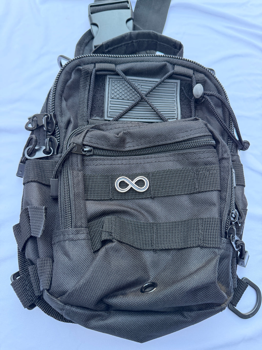 Infinity sign pin displayed on a black tactical backpack 