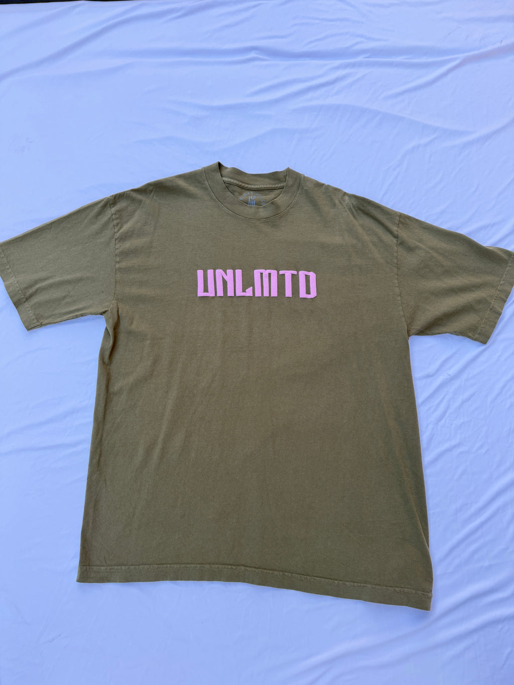 Olive Green t shirt with pink puff print letters spelling “UNLMTD”