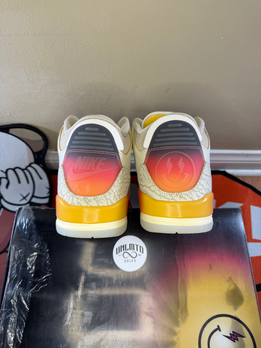 Back view of shoe. Nike air on left heel. J Balvin logo on the right heel. Sunset details in the heal as well