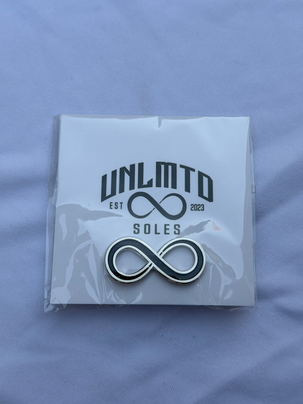 UNLMTD Soles Pin Black infinity sign with silver outline 